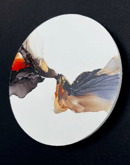 Abstract art with meaning featuring black, brown, orange and gold colours unfurling like wings on a white circle base, shown on a black wall.