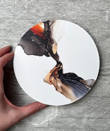 Day and night abstract art featuring autumn and gothic colours of black, orange, brown and gold that sweep out like wings on a white round panel set on a stone wall.