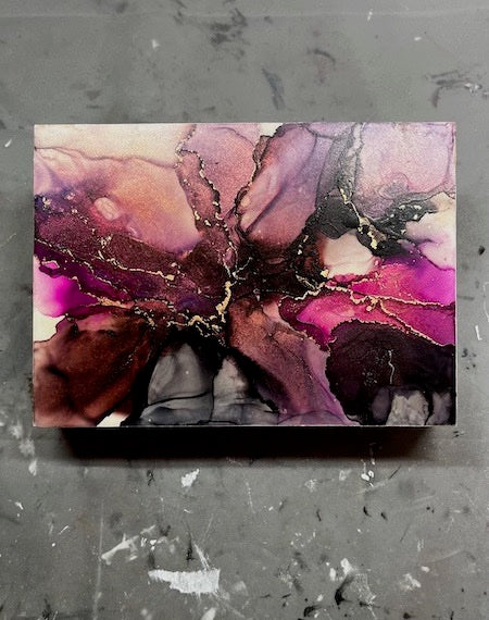 Abstract art of space featuring pink, purple, black, copper and gold colours on a textured grey background; celestial wall art.